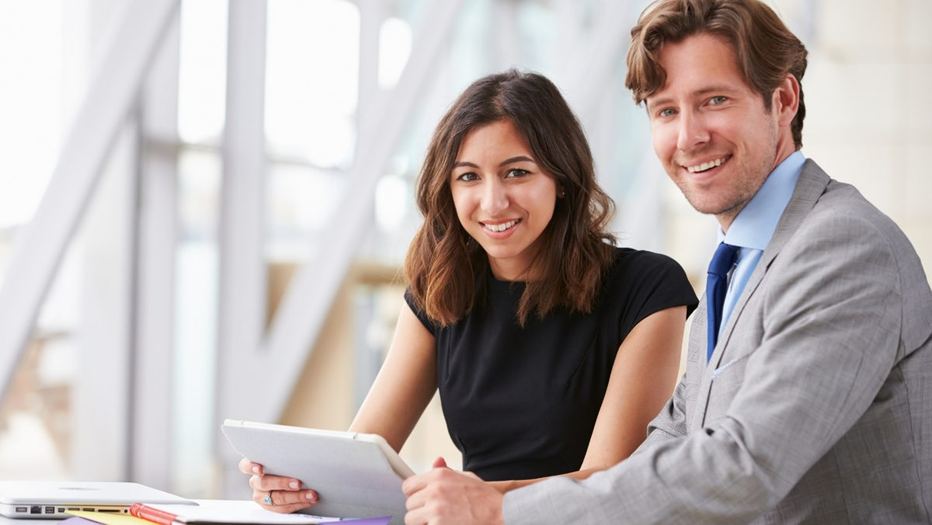 Two colleagues reviewing information on a tablet