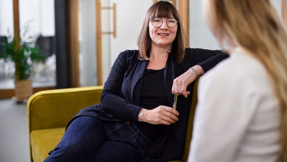 Smiling woman with glasses talking with a colleague about workplace menopause support