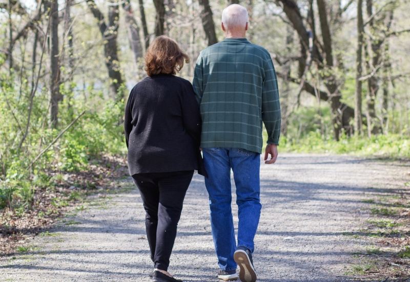 Older couple walking together on a woodland path