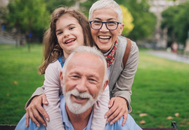 Grandparents smiling with their granddaughter in a park