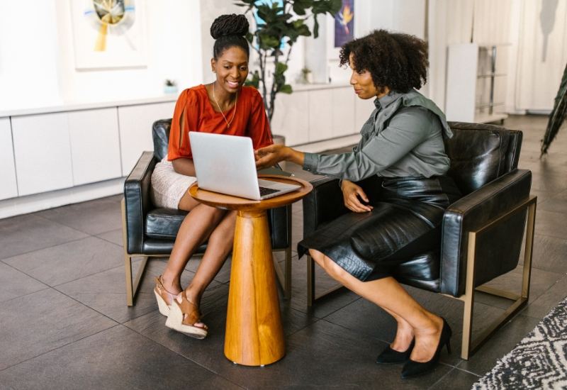 Two women talking over a laptop in an office