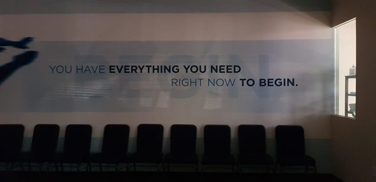 Wall slogan reading "You have everything you need right now to begin" above a row of dark chairs