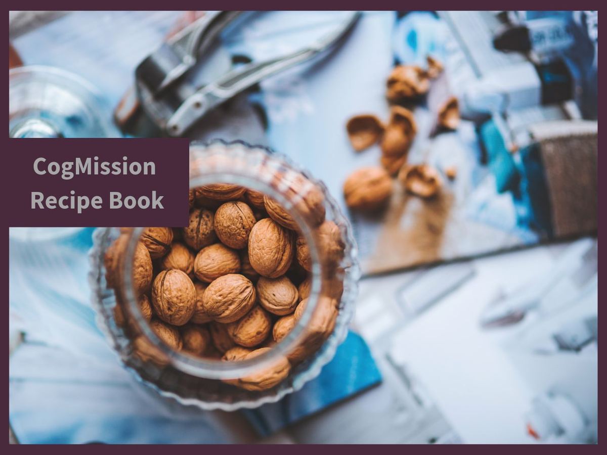 CogMission Recipe Book cover with a glass jar of whole walnuts beside a nutcracker and cracked shells