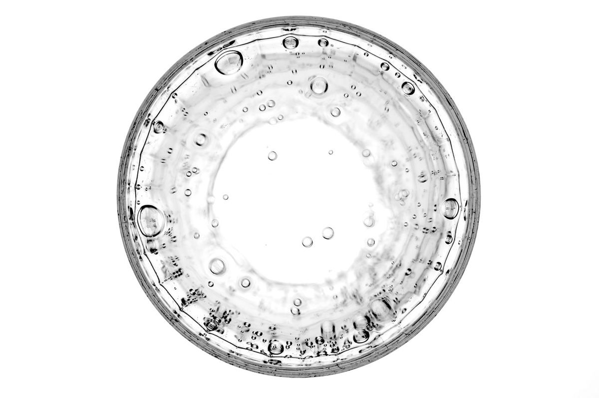 Overhead view of a clear glass of fizzy water with small bubbles clinging to the sides